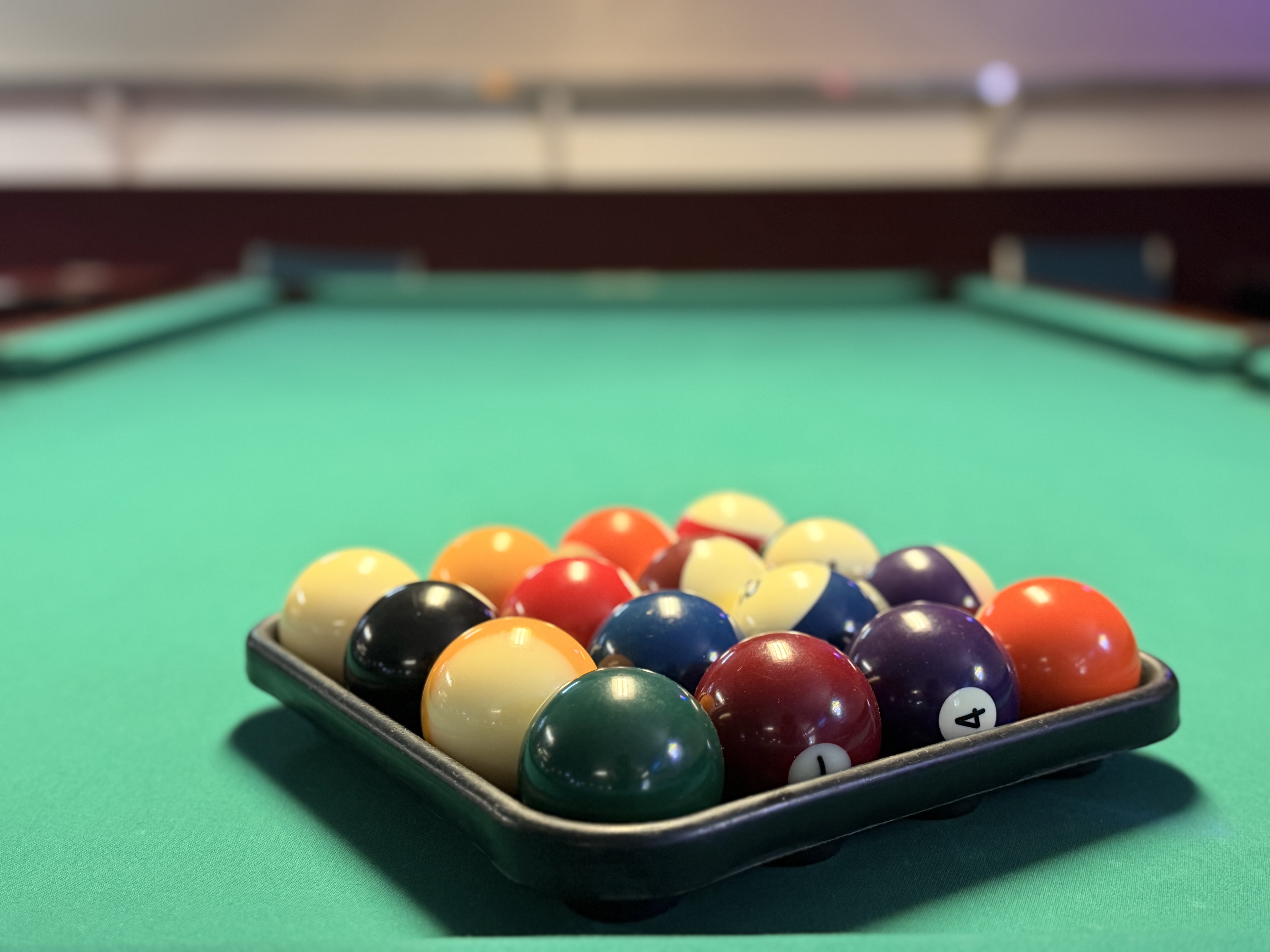 A rack of pool balls ready to break on green felt