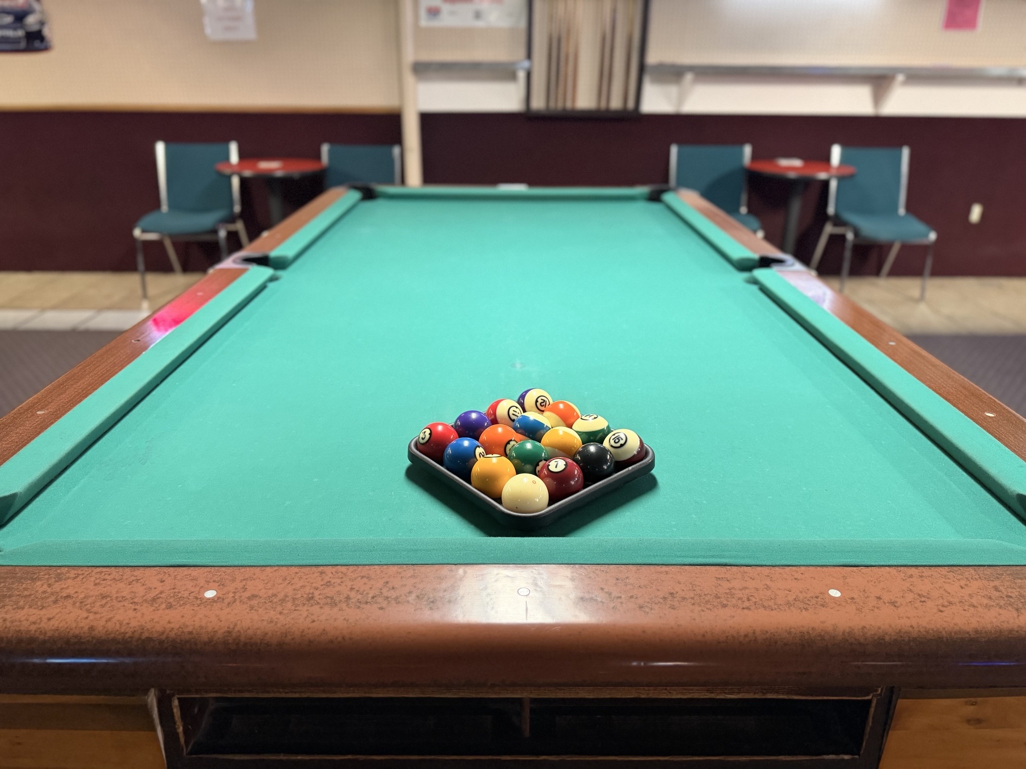 A green felt pool table with a fresh rack of balls